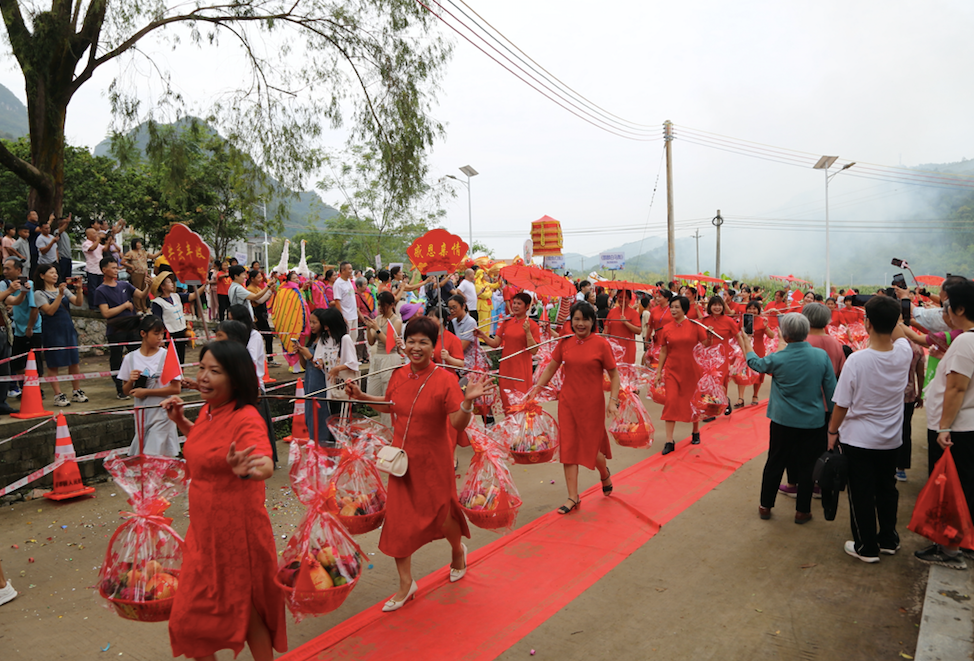 淘潭节队伍沿村道前行，返乡亲友和村民在两侧相迎